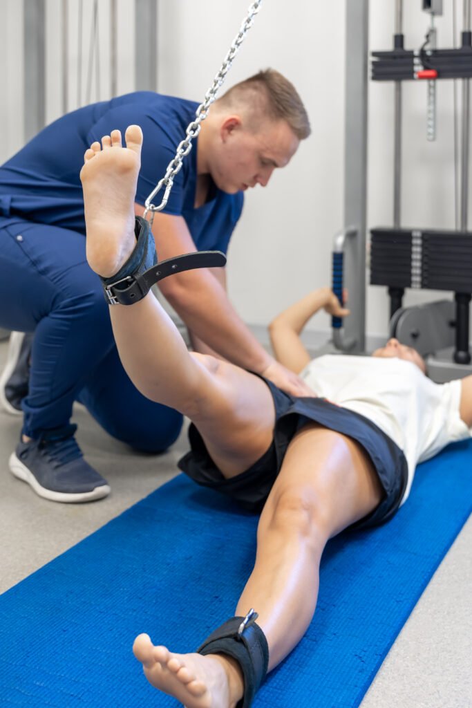 woman does legs raise exercise, therapist helping with mechanical disorders.